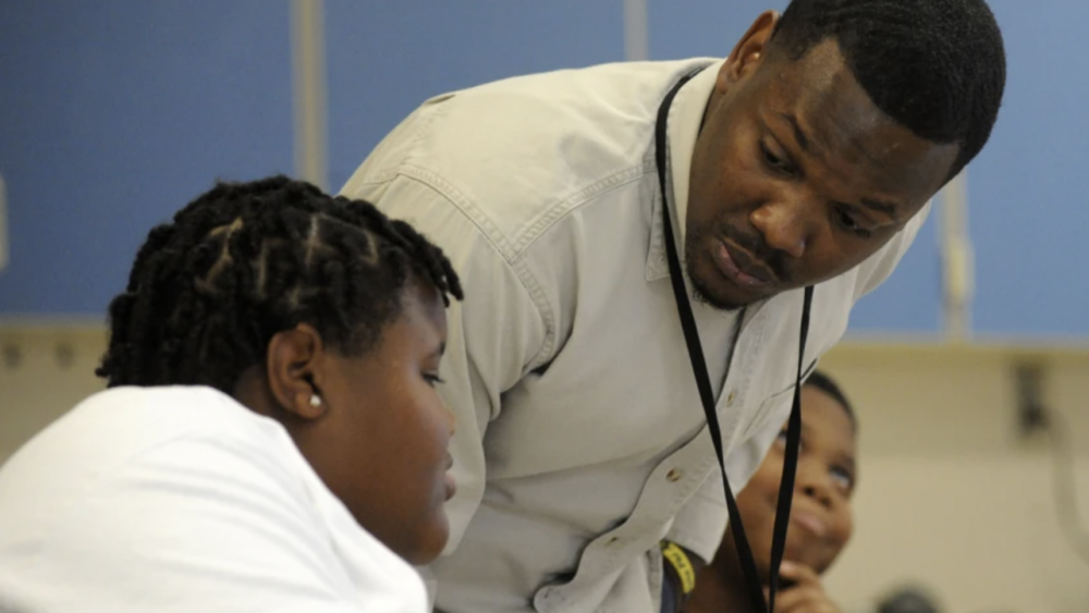 Black male teacher speaking with a Black male student