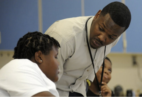 Black male teacher speaking with a Black male student