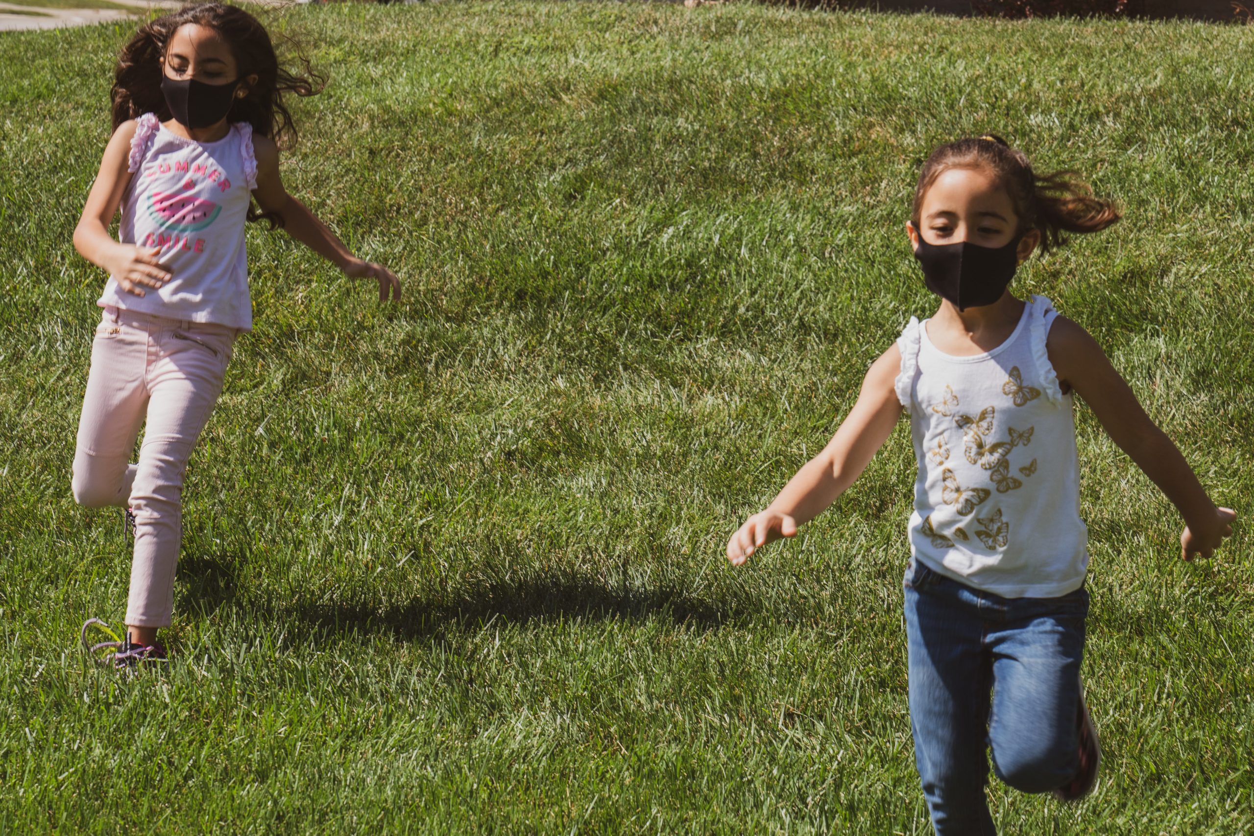 Two kids with masks running in field