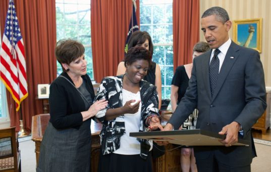 Lois Curtis hands a painting to President Barack Obama in the Oval Office