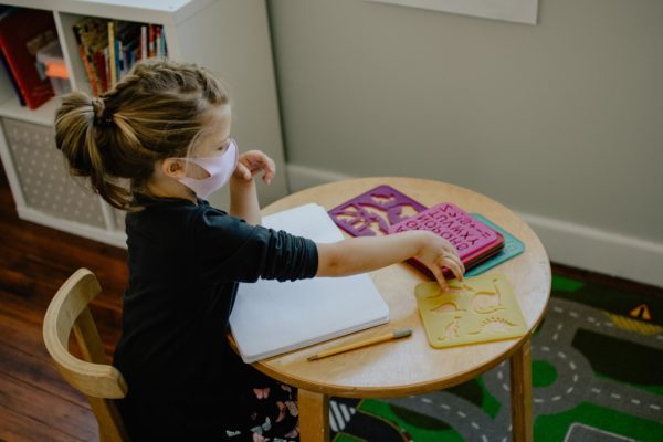 Young girl sitting at a school table wearing a face mask